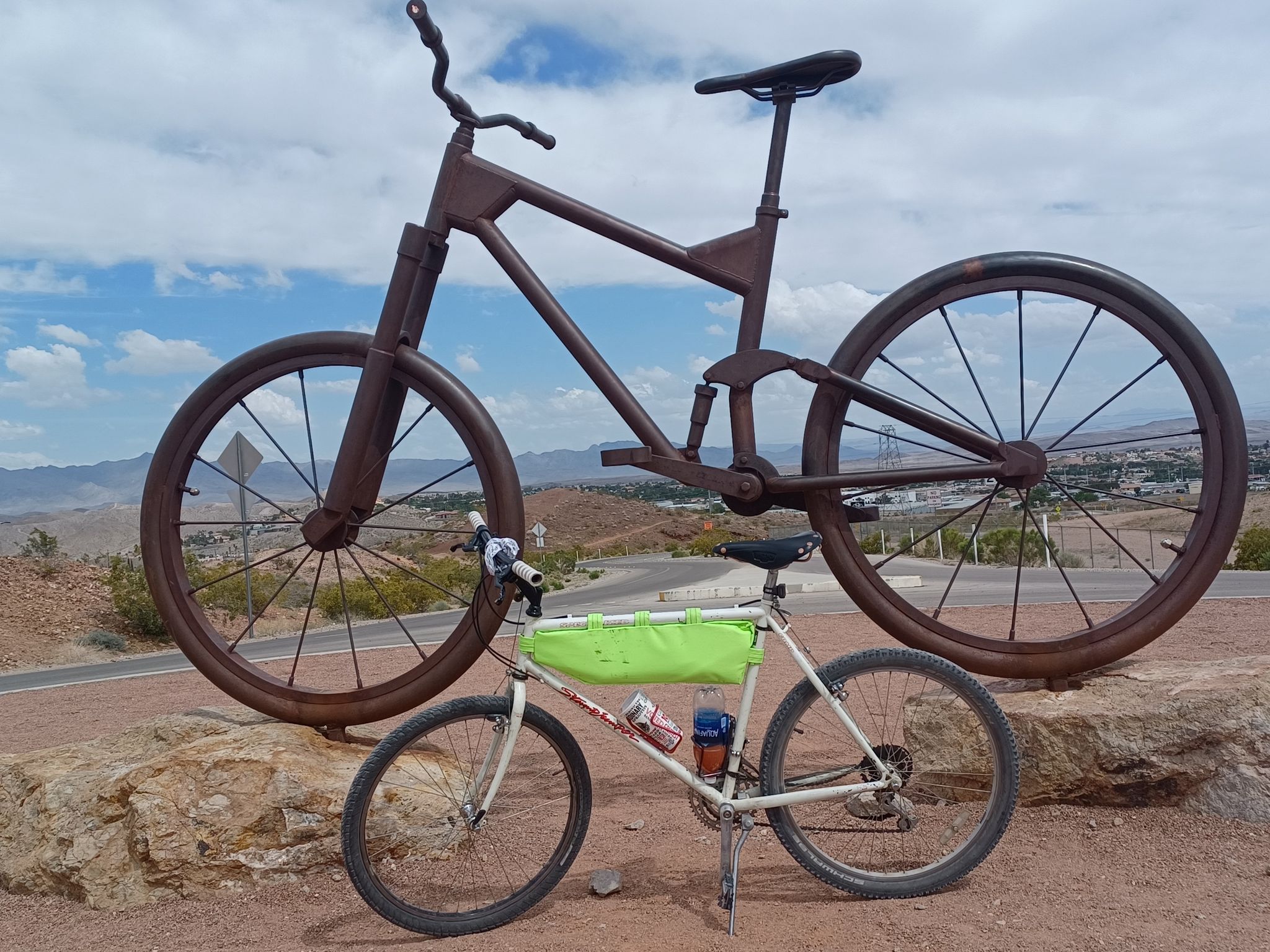 A small bicycle rests before a giant metal bicycle sculpture outdoors. - River Mountains Loop Trail