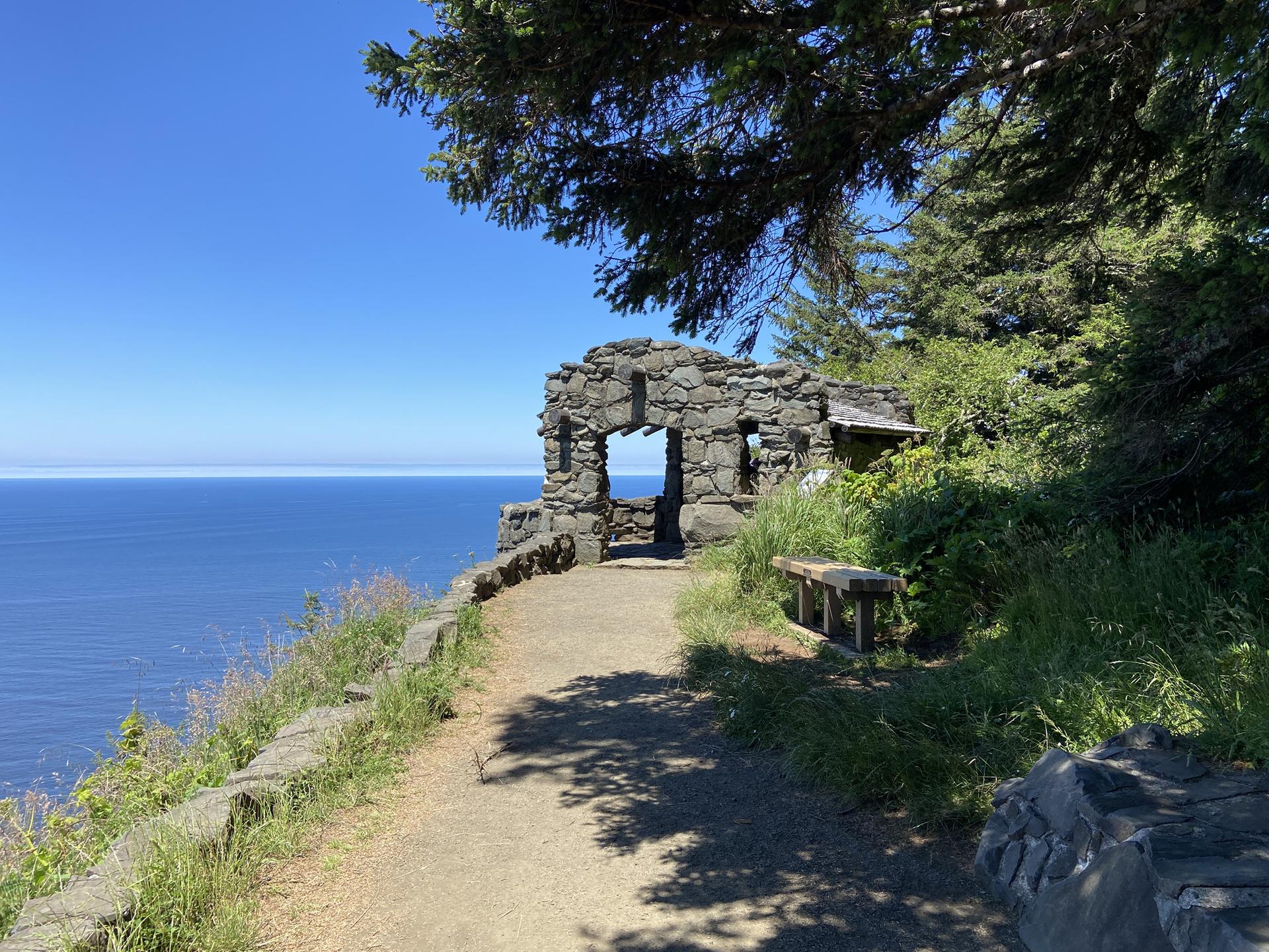 A stone structure overlooks a vast blue ocean on a sunny day.
