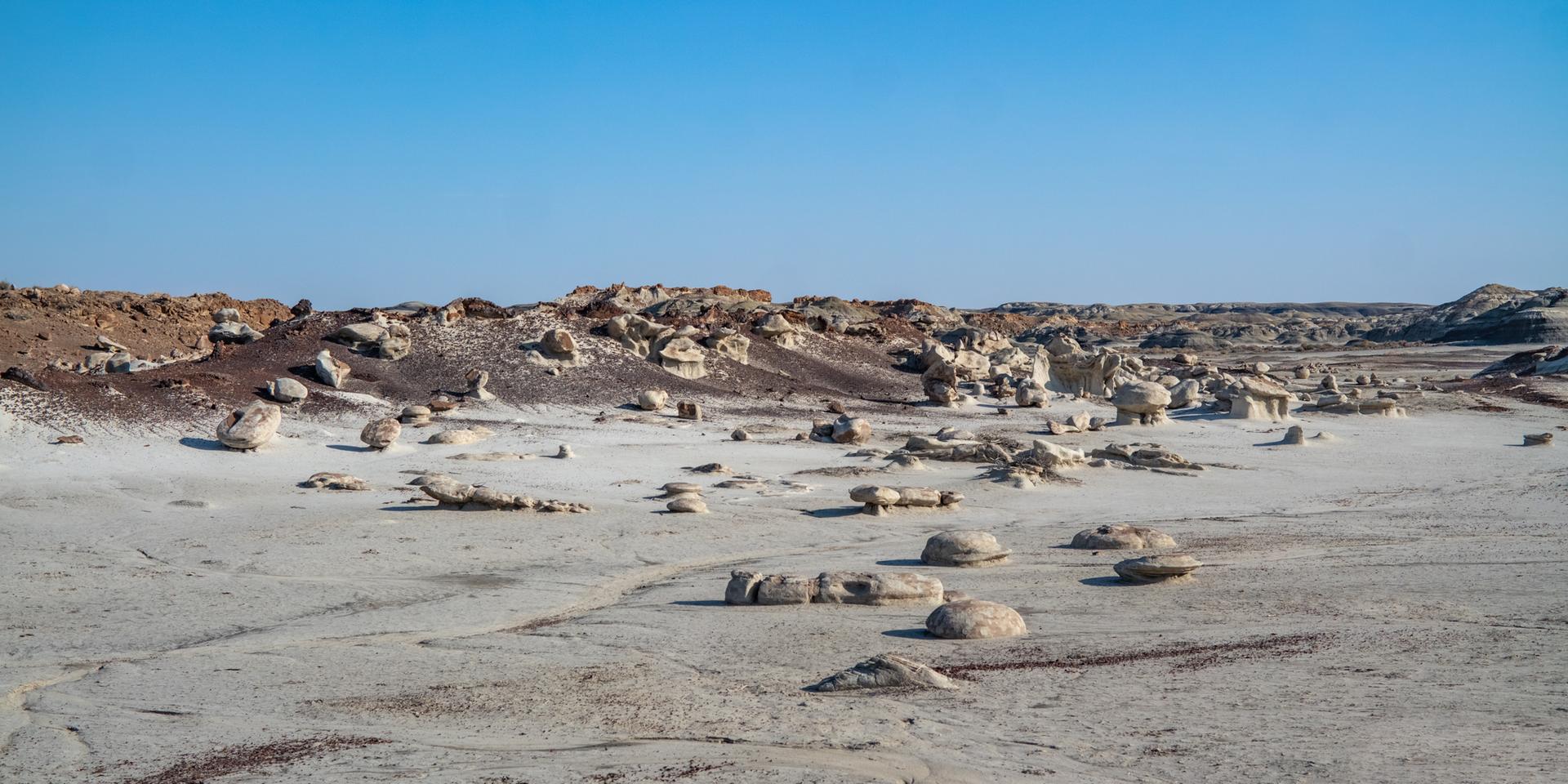 Wide view of a desert landscape with many scattered rock formations and hoodoos.