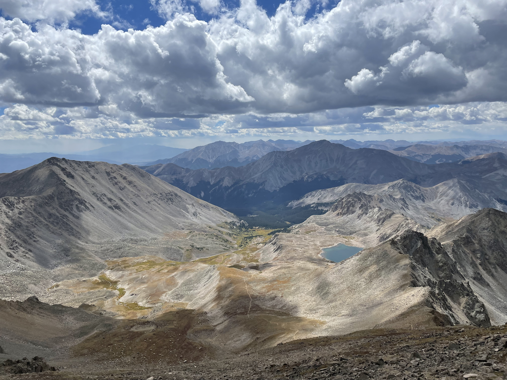 A vast panoramic view of rugged mountain ranges under a cloudy sky.