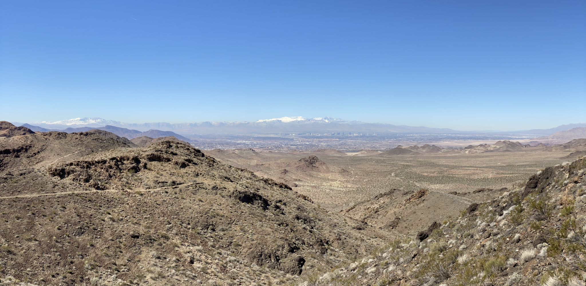 Vast desert landscape with rolling hills and distant snow-capped mountains under a clear sky. - Bootleg Canyon Trailhead – Giant Bicycle loop from Boulder City Hospital