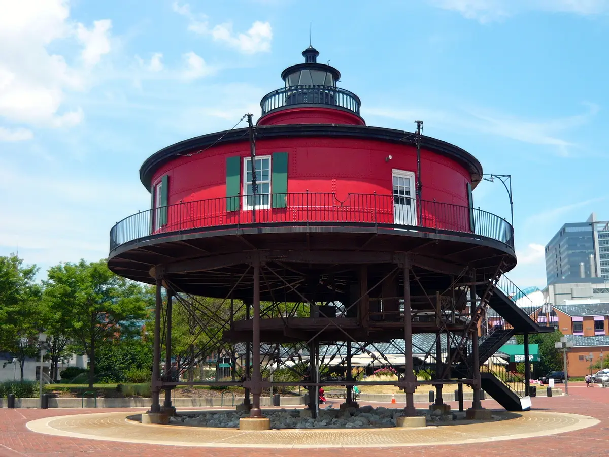 A unique red, round lighthouse-style building on stilts with a black railing.
