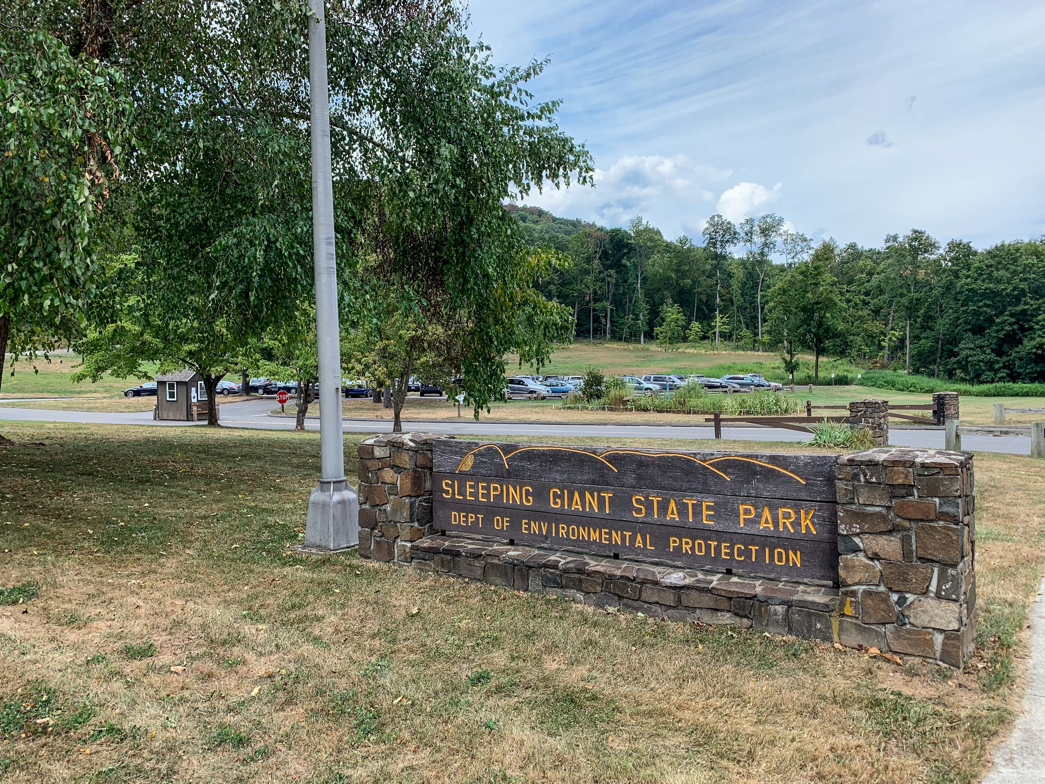 A large wooden sign on a stone base in a grassy park area. - Tower Trail