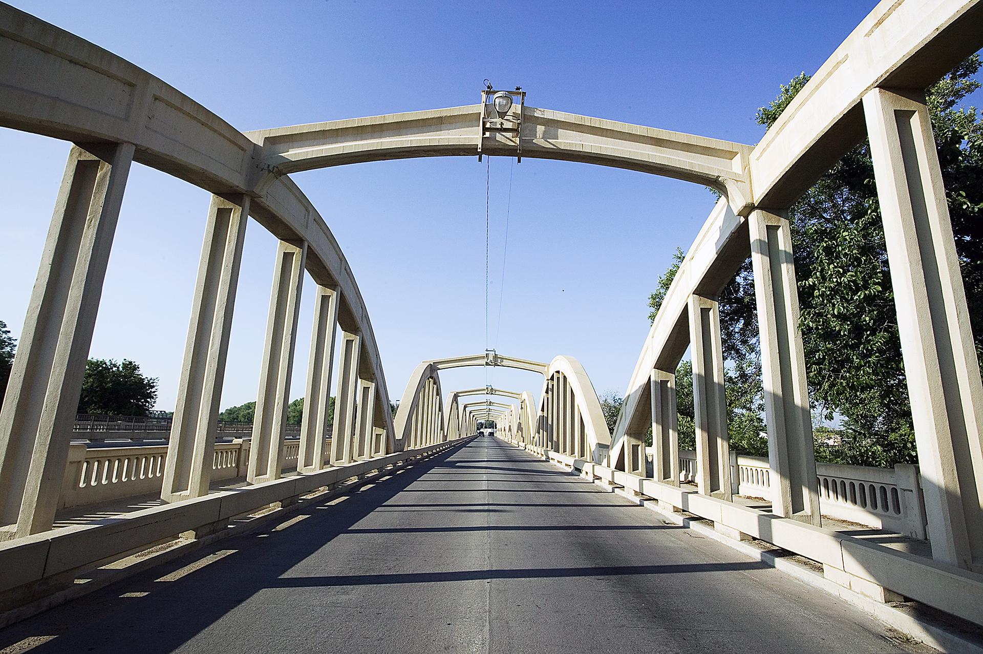Long concrete bridge with multiple arches extends into the distance under clear sky.