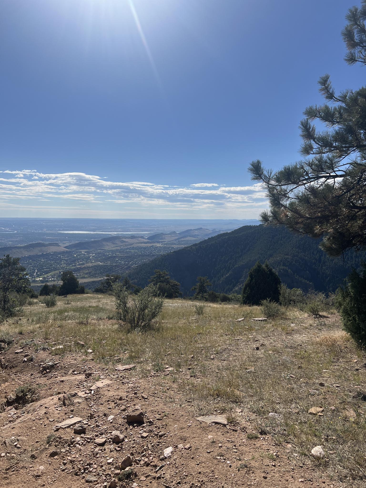 Sunny panoramic view from a hilltop overlooking a vast valley and plains.