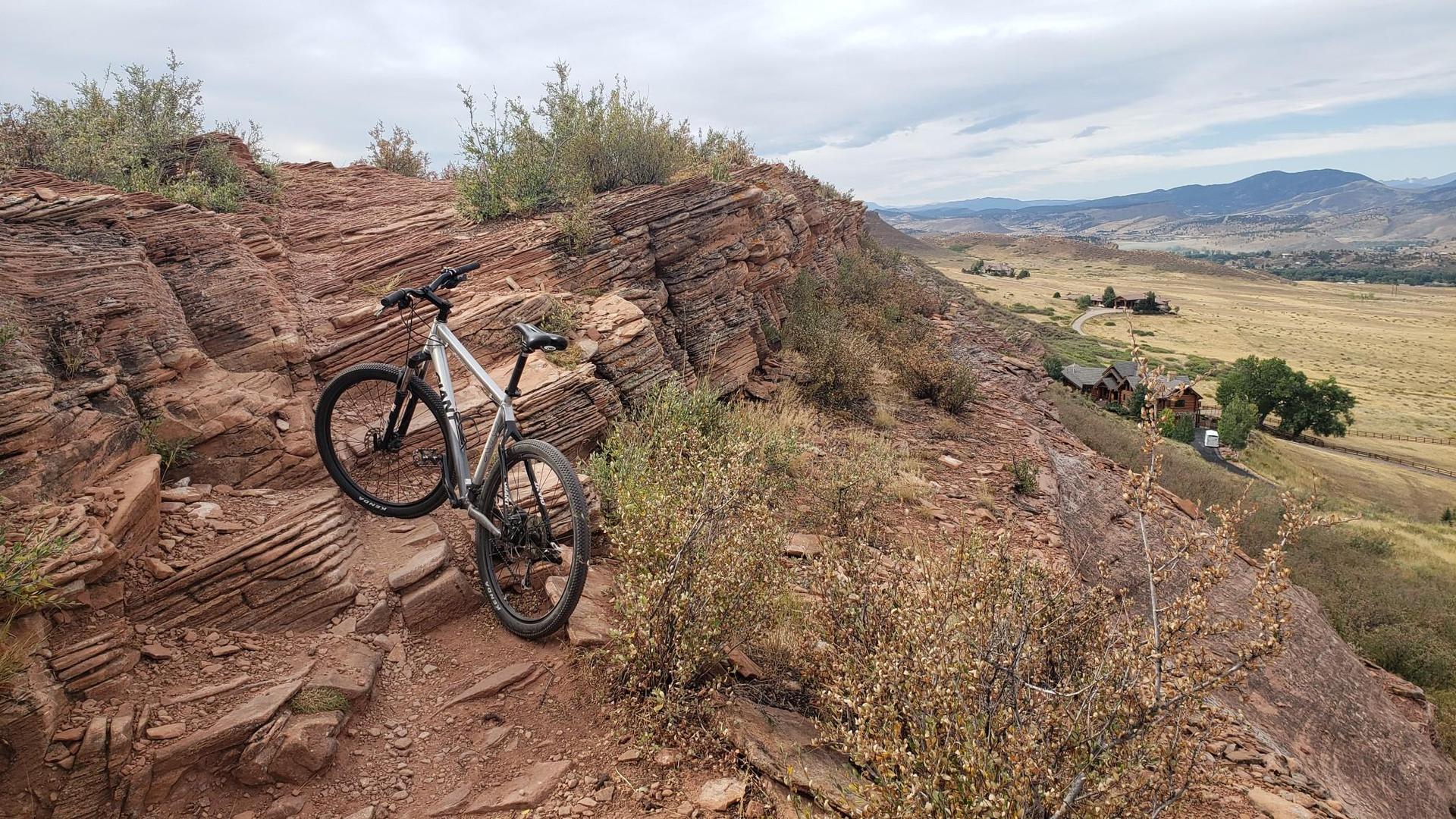 Mountain bike parked on a rocky, steep trail overlooking a valley.