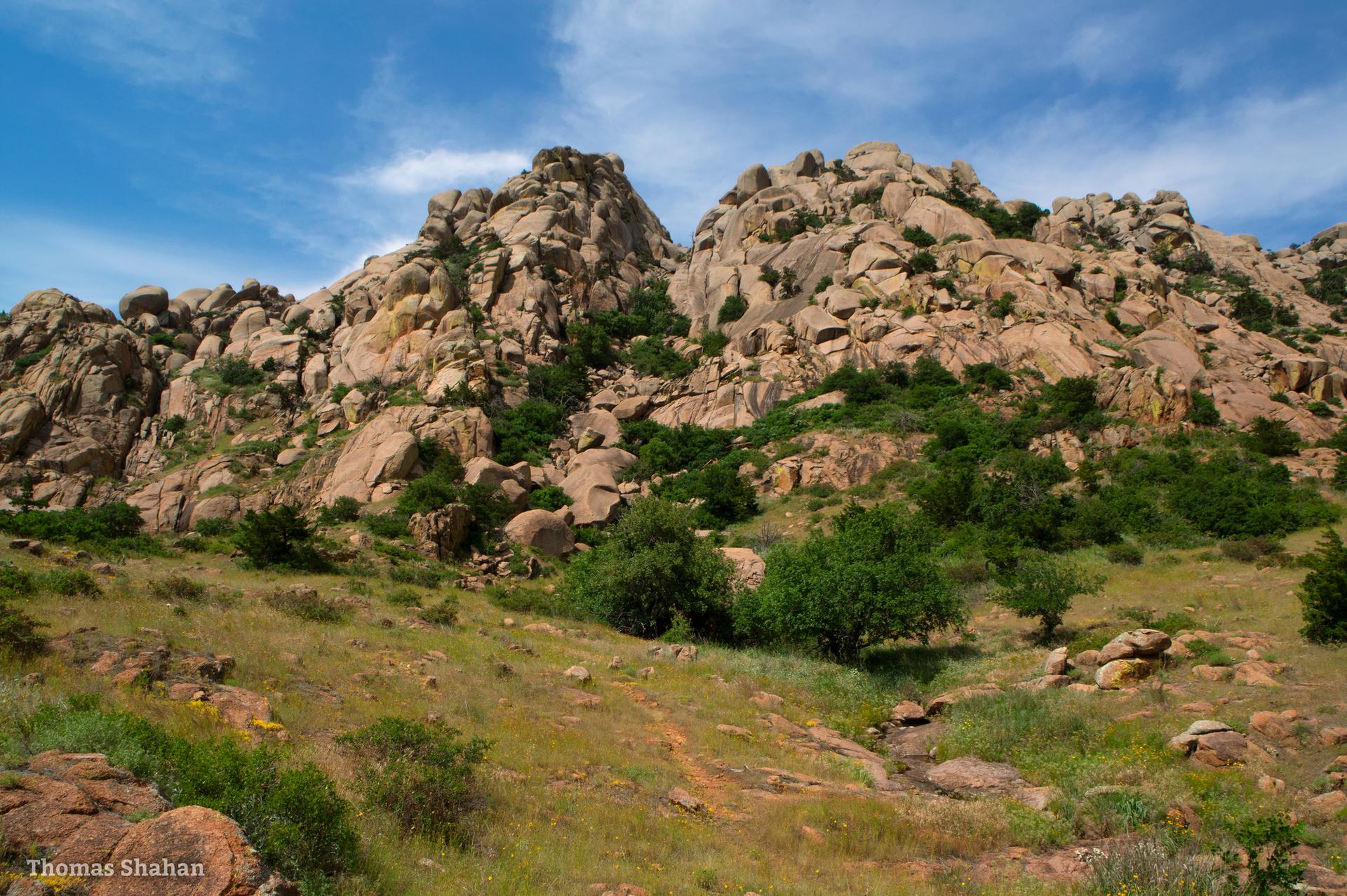 Massive rocky mountains under a bright blue sky with sparse green vegetation.