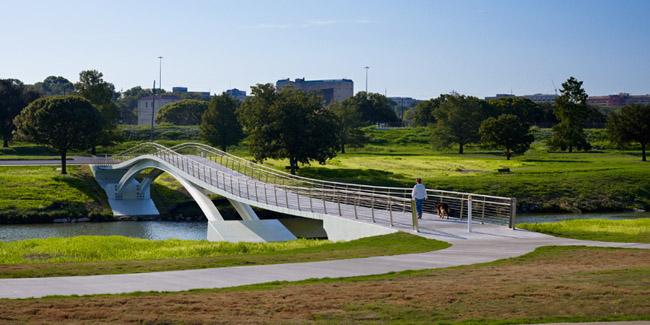 Person walking on a modern white pedestrian bridge over a river.