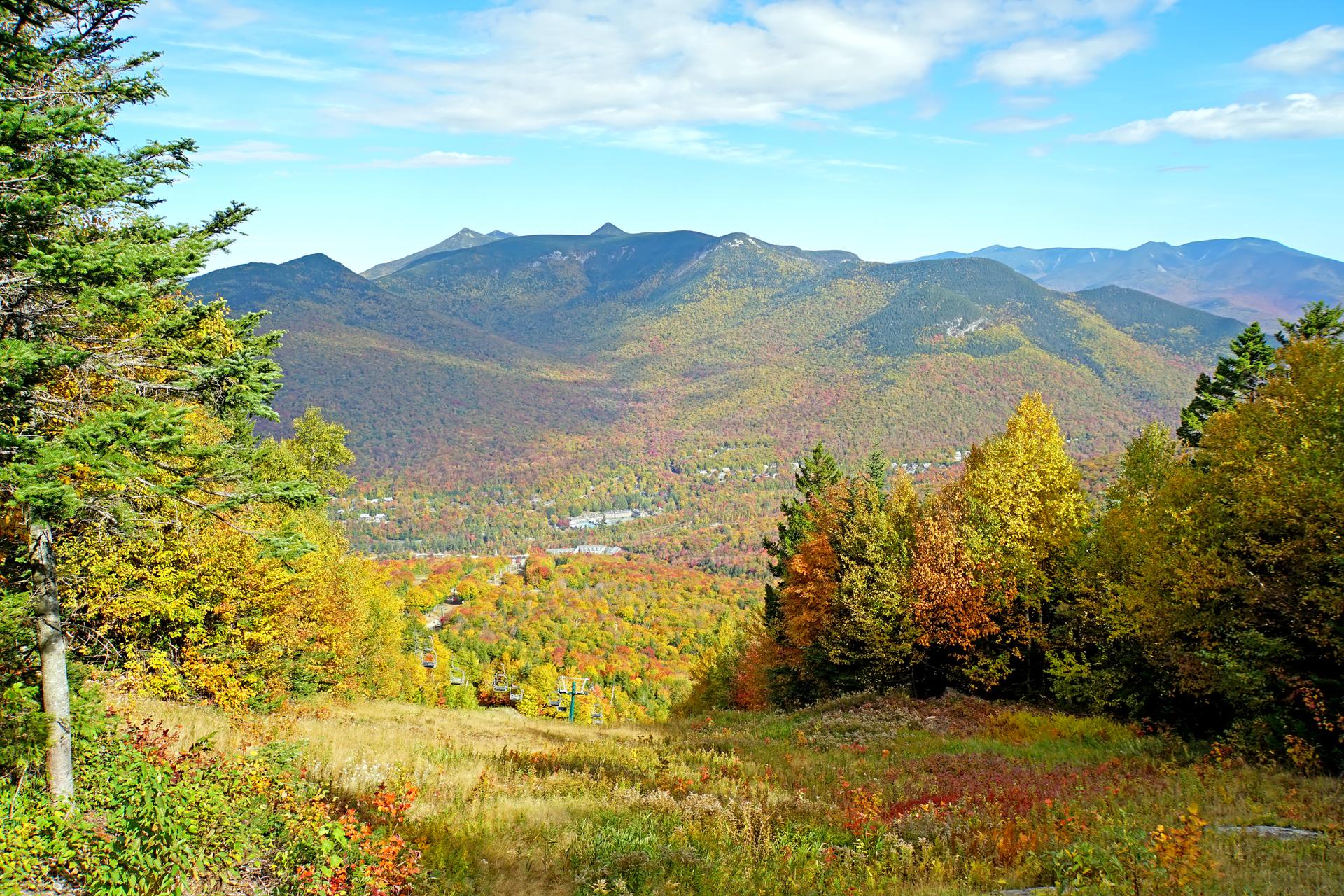 Panoramic view of a vibrant autumn mountain landscape under a clear blue sky.
