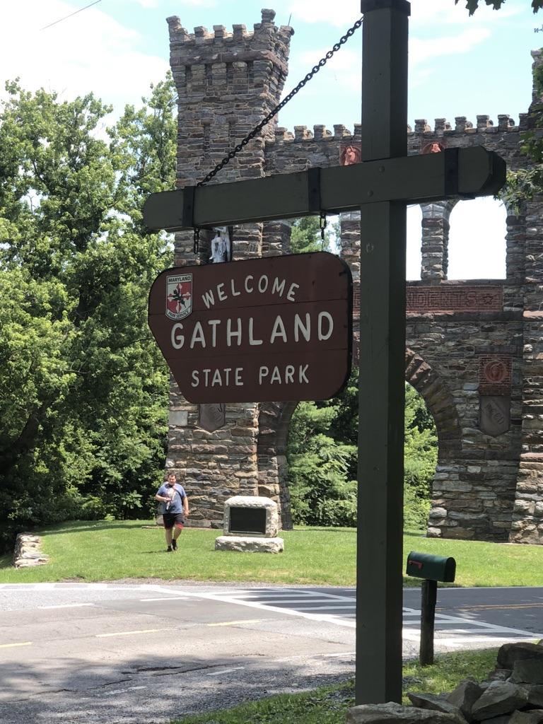 Welcome sign, stone castle-like structure, and person walking on grass.