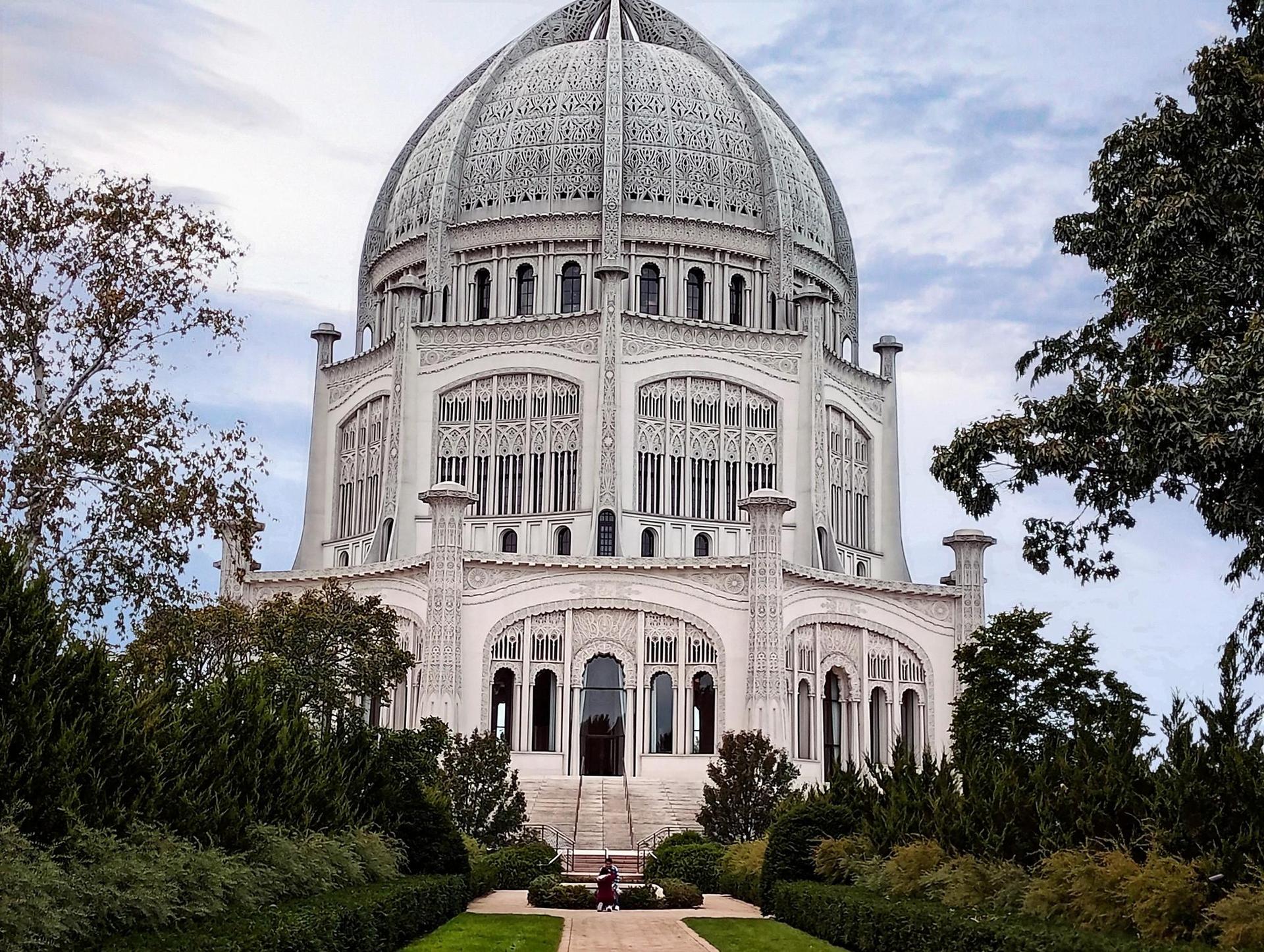 Ornate domed building surrounded by lush green gardens on a bright day.