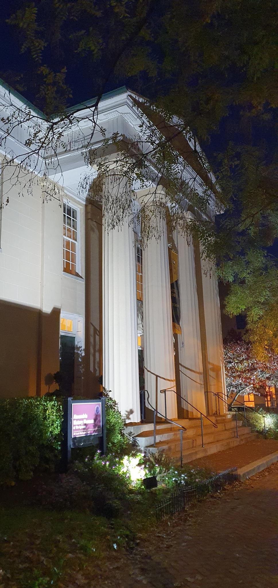 Illuminated classical building with large columns at night.