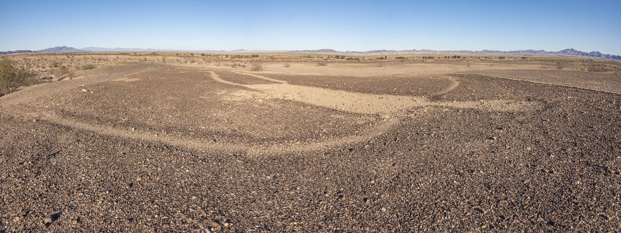 Vast, dry desert landscape with faint ground patterns under a clear blue sky. - Blythe Intaglios Trail
