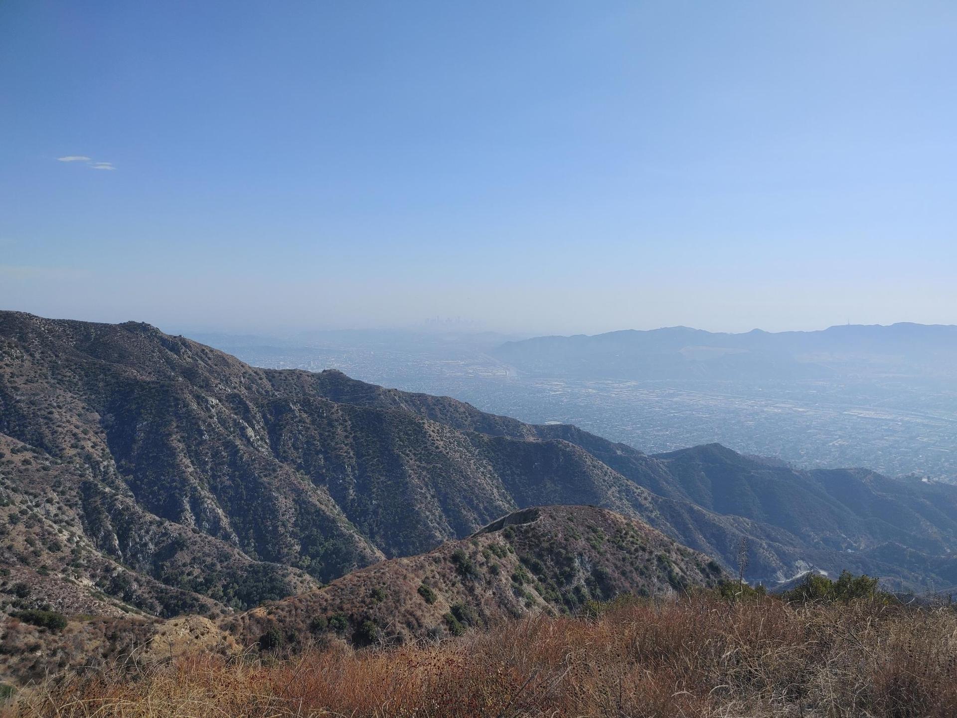 Expansive view of rugged, dry mountains and a distant hazy valley.