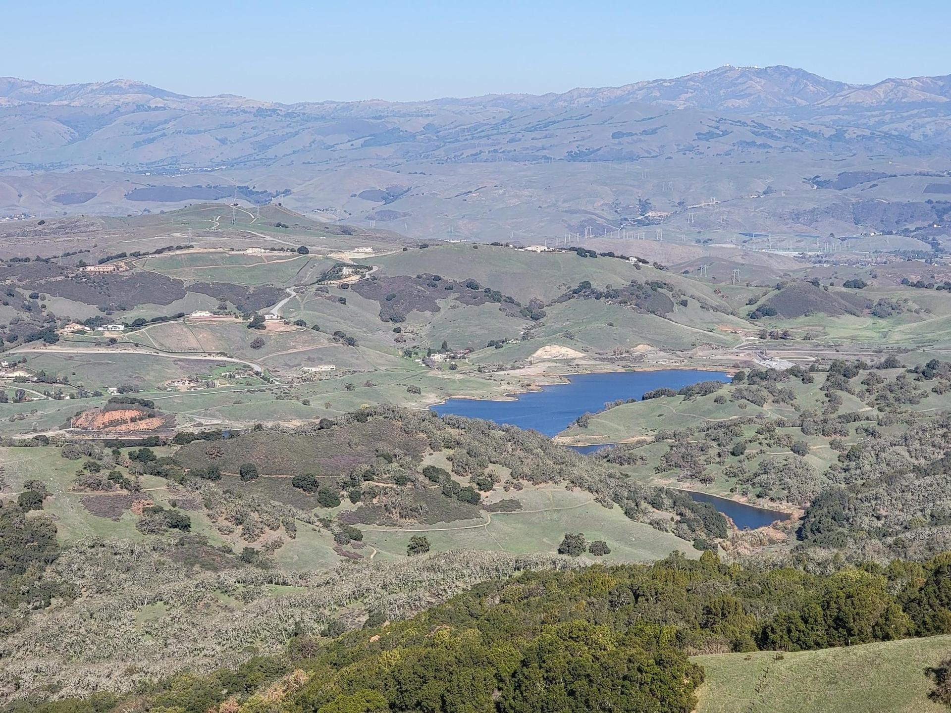 Panoramic view of rolling green hills, distant mountains, and two blue lakes.