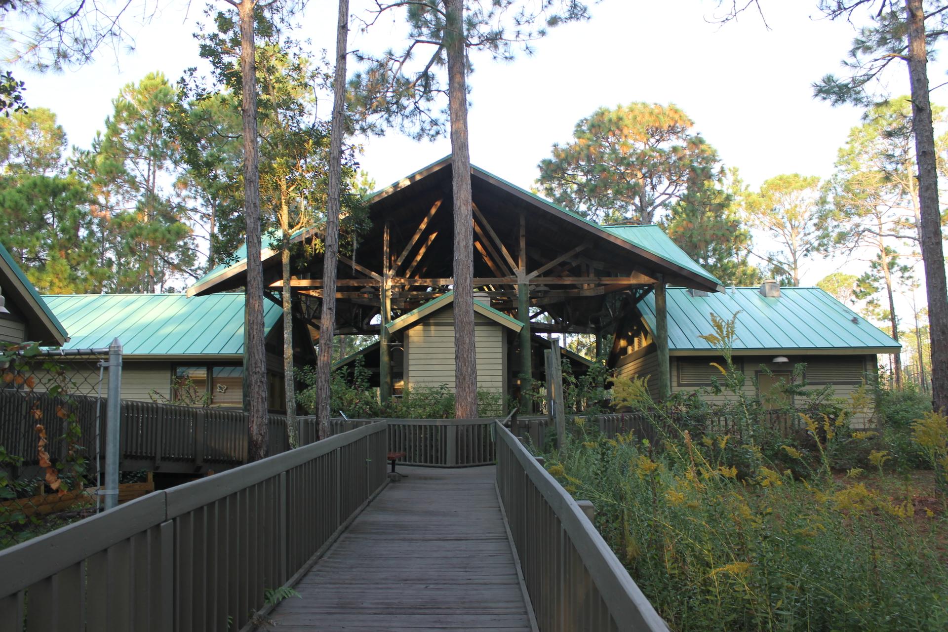 Wooden boardwalk leading to a large building with a green roof.