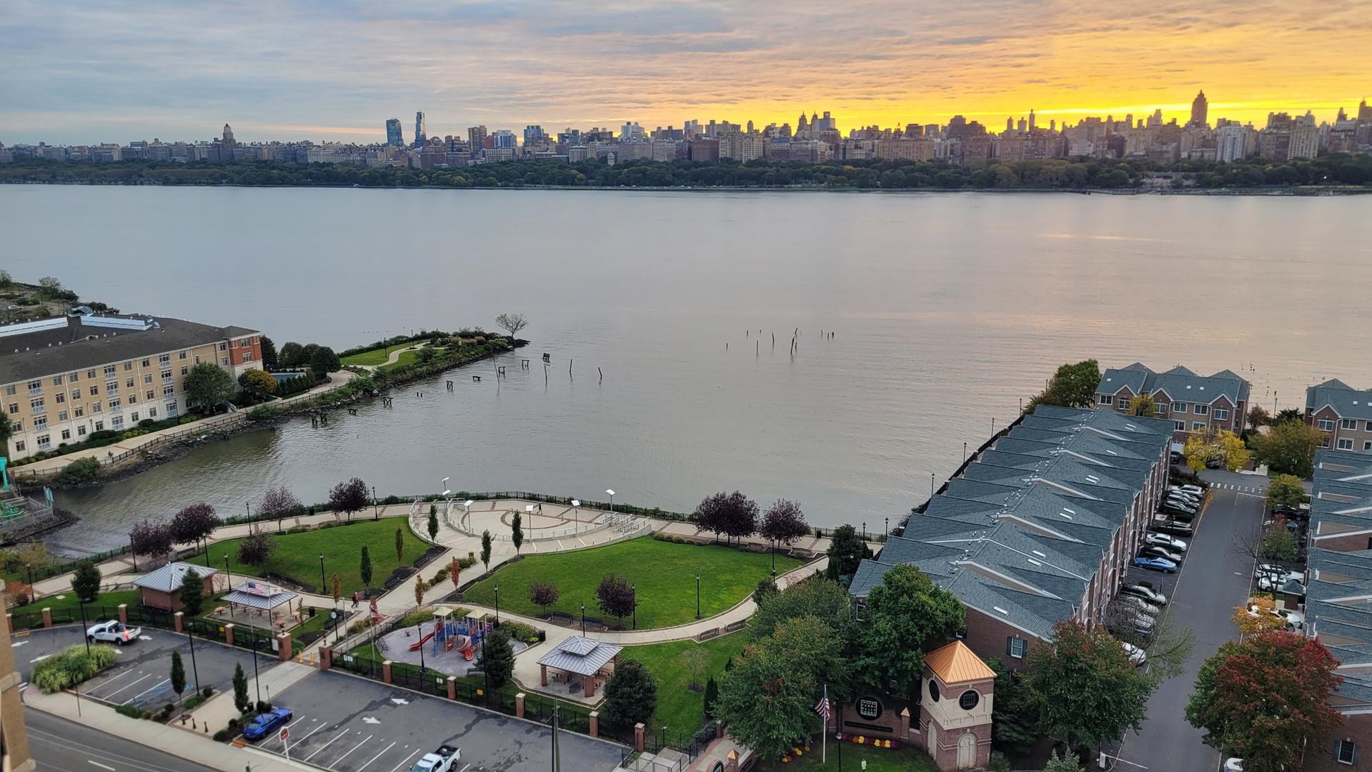 Aerial view of waterfront park and buildings, city skyline at golden sunset.