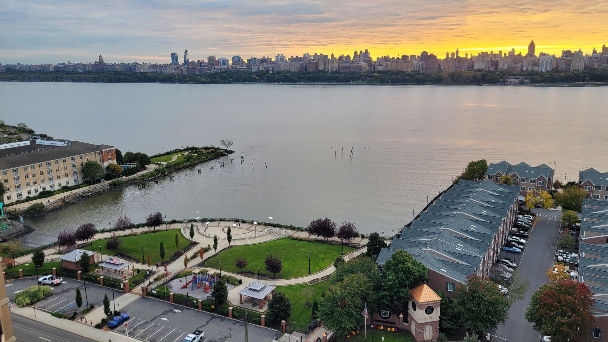 Aerial view of waterfront park and buildings, city skyline at golden sunset. - Hudson River Waterfront Walkway