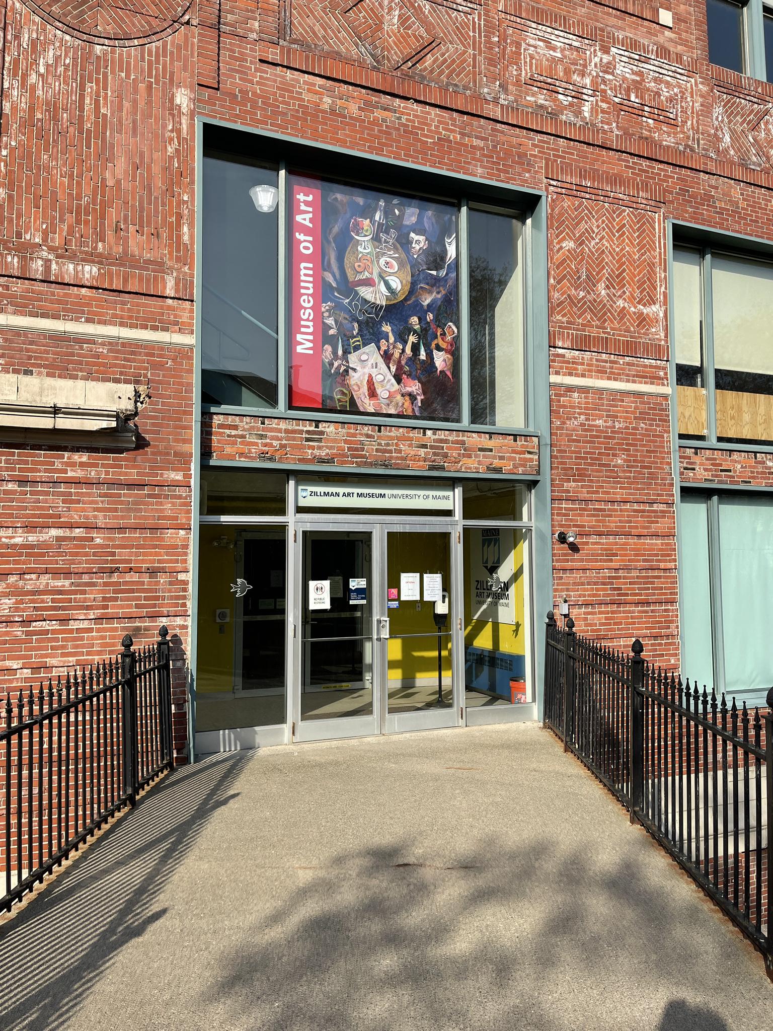 Brick building entrance with "Museum of Art" sign, sunny.