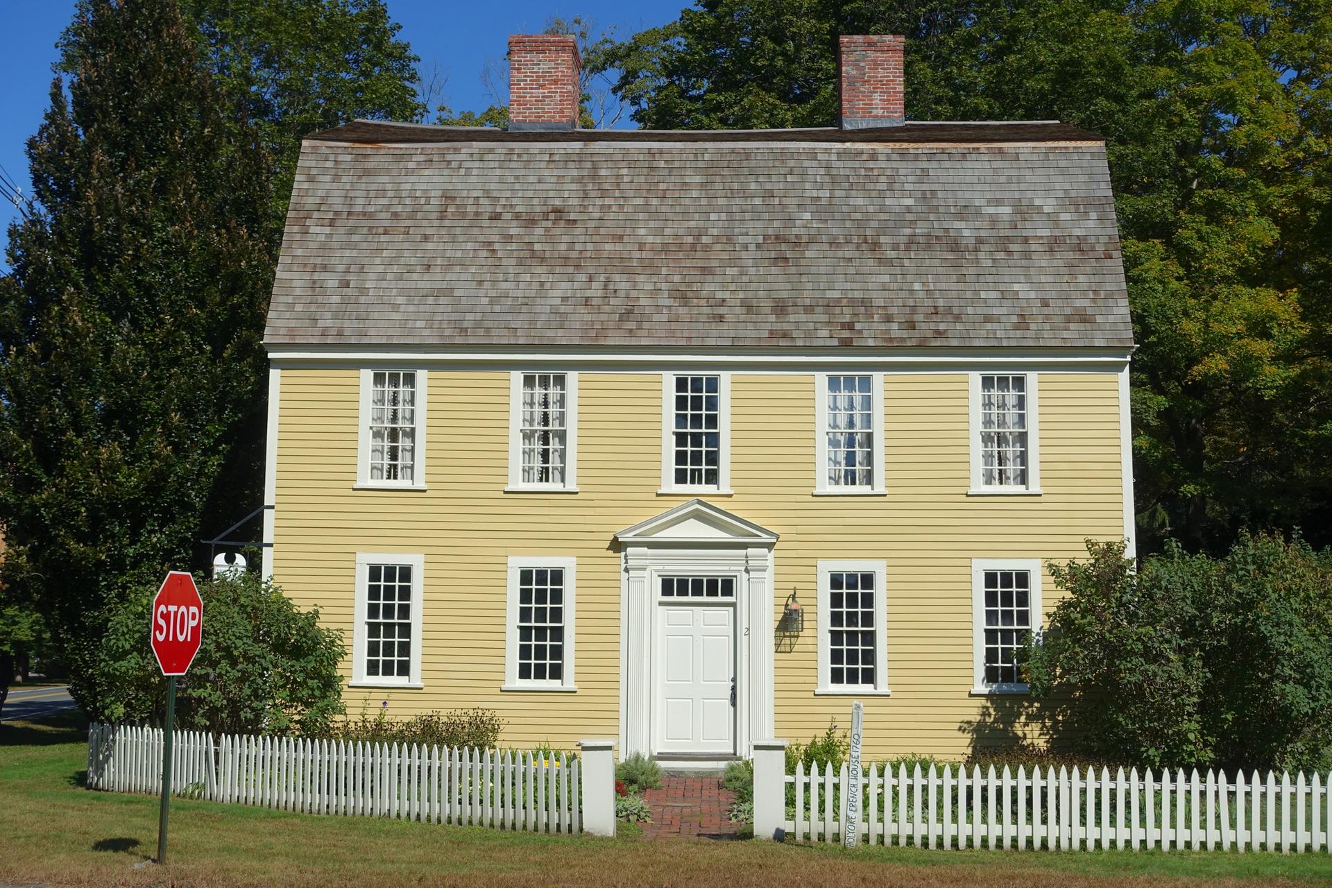 A bright yellow house with a white picket fence under a clear sky.