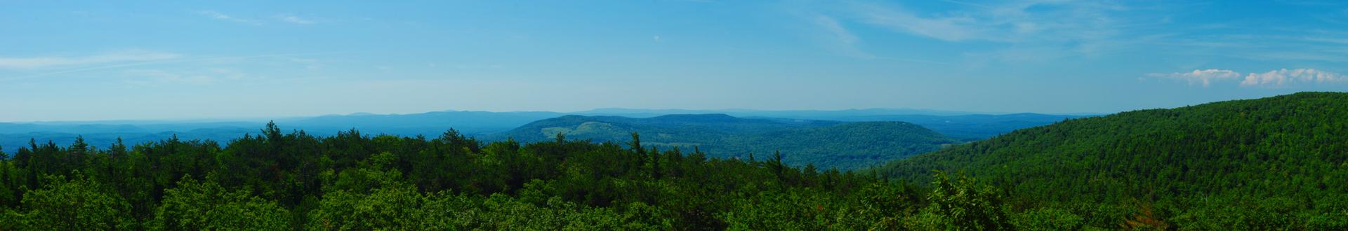 Panoramic view of distant forested mountains under a clear blue sky.
