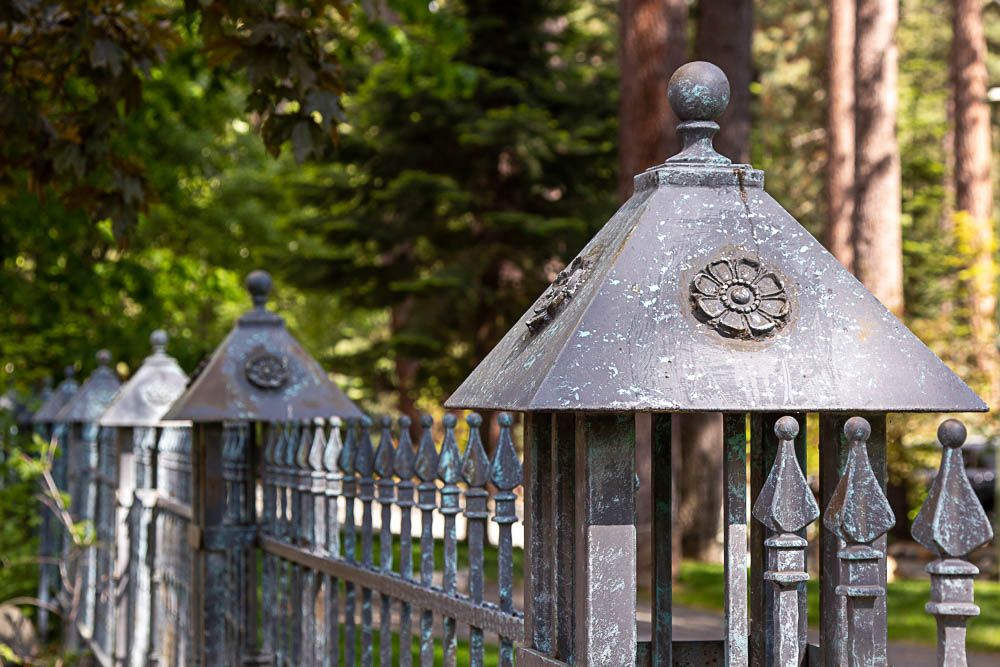 Close-up of an ornate, weathered metal fence with trees in soft focus. - Incline Village to Mt Rose Summit loop