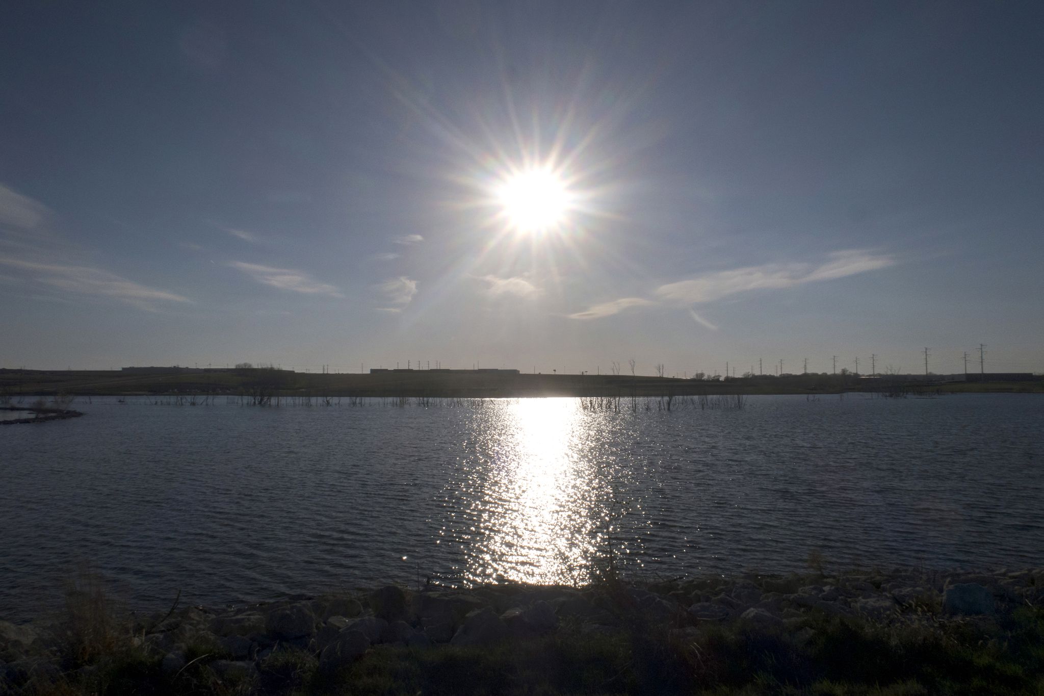 Bright sun shines over a wide body of water, reflecting on the surface. - Prairie Queen Trail Loop