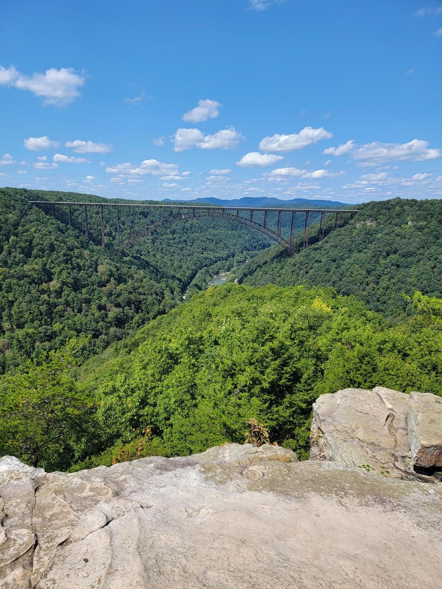 A large arch bridge spans a deep, forested gorge under a clear blue sky. - Long Point via Fayetteville Trail