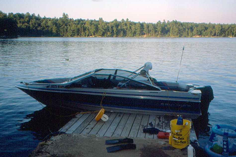 Motorboat docked at a wooden pier on a calm lake with a forested shore. - Beech Hill Pond loop