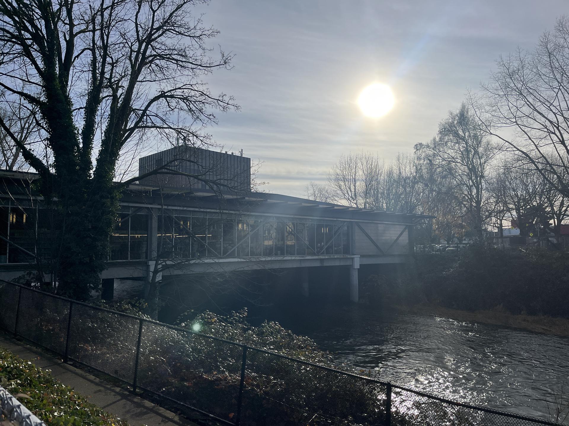 Building over a river with bright sun in a hazy sky.