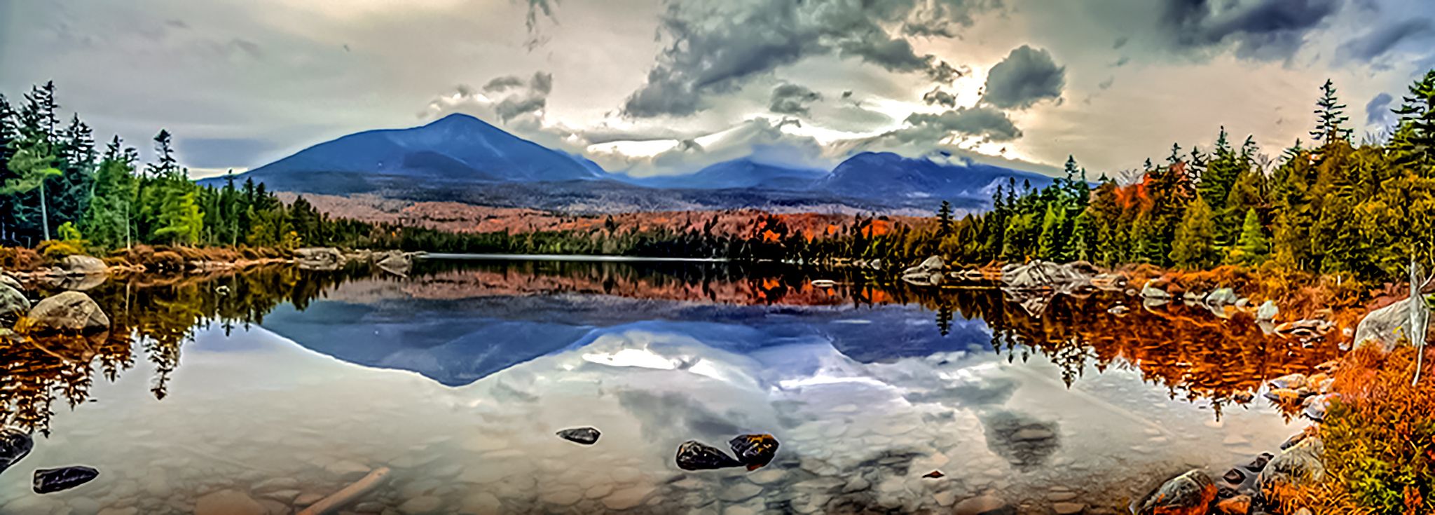 Panoramic mountain lake reflects peaks and autumn trees under dramatic cloudy sky. - Lincoln to Millinocket via East Coast Greenway