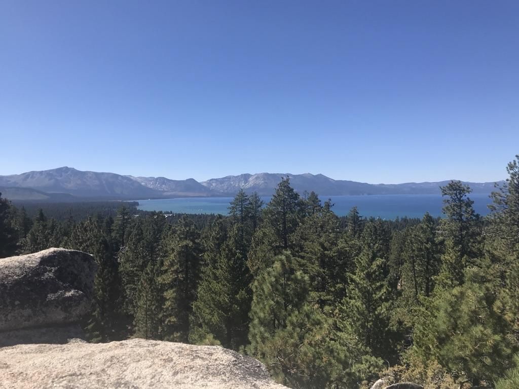 Scenic overlook of a vast forest, a serene blue lake, and distant mountains. - Van Sickle Trail