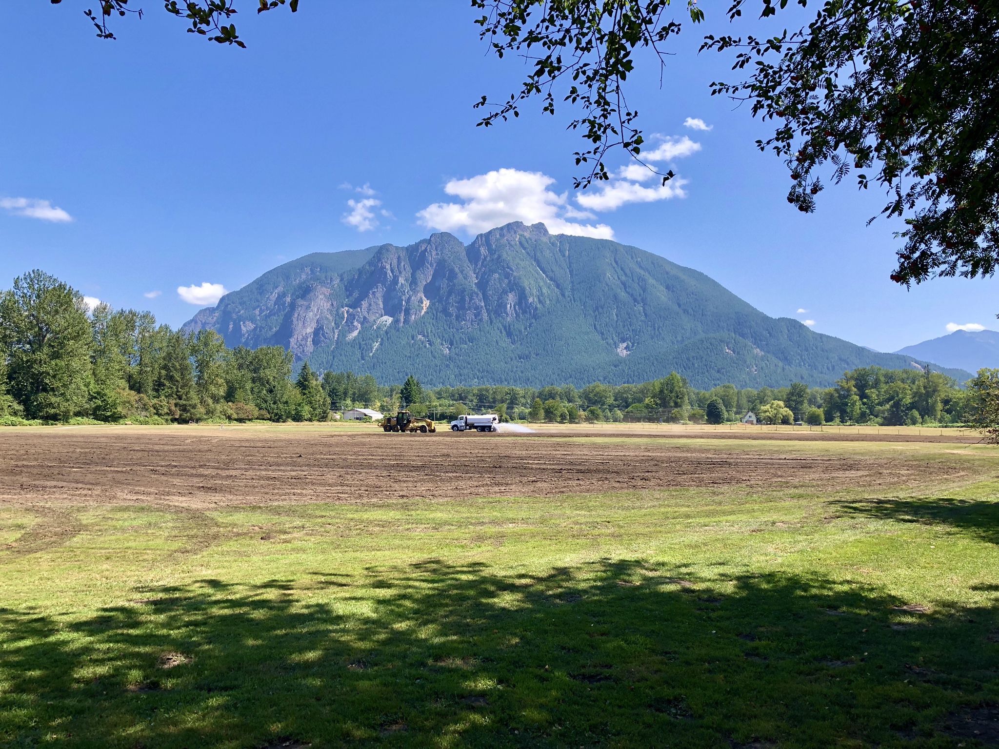 Bright day with a large mountain overlooking a green and brown field. - Snoqualmie Valley and Tollgate Farm Loop