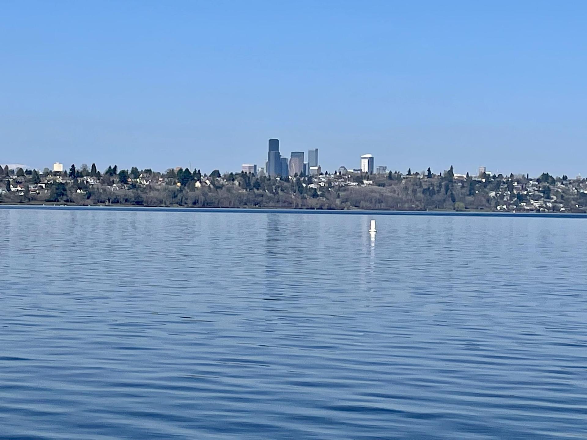 A city skyline visible across a calm lake under a clear blue sky.
