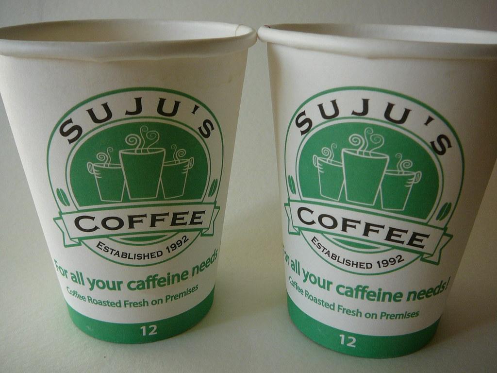 Two white and green coffee cups with a "Suju's Coffee" logo.