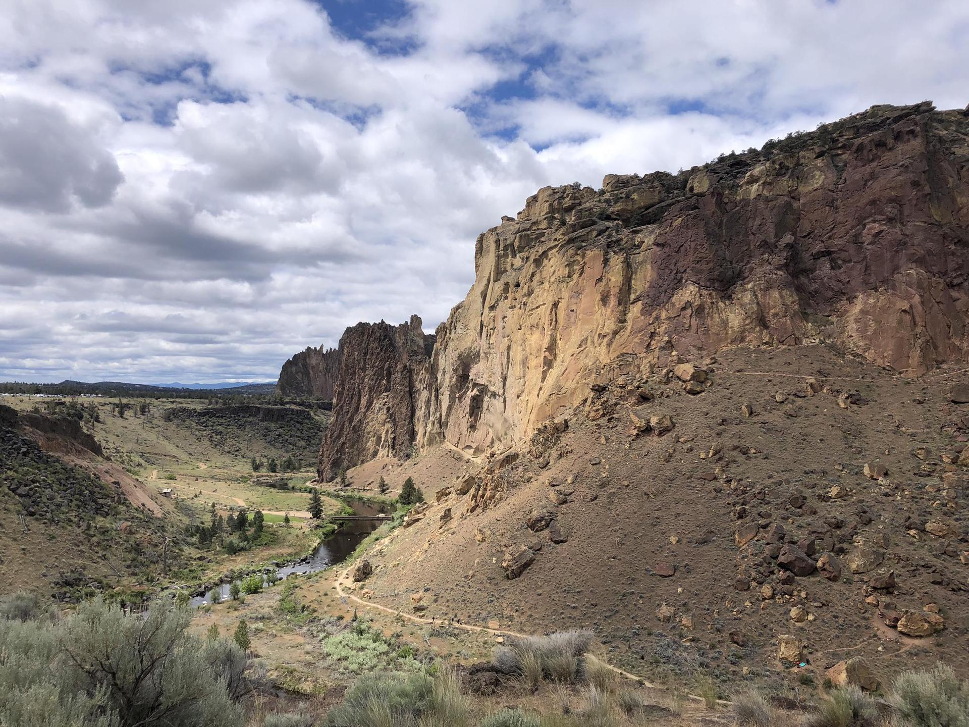 A deep canyon with towering rocky cliffs, a river, and cloudy sky.