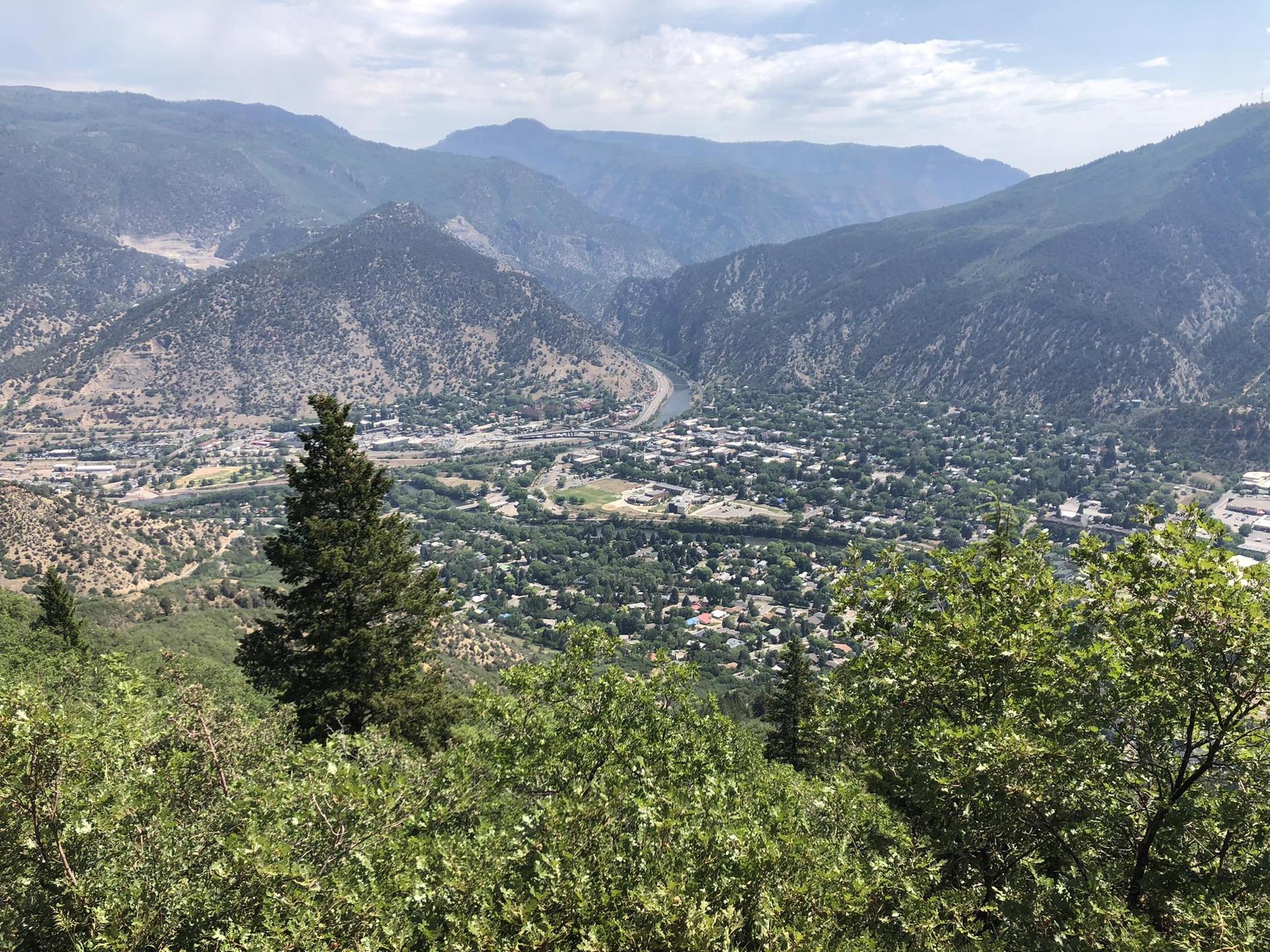 Overlook of a town in a green mountain valley with a river.