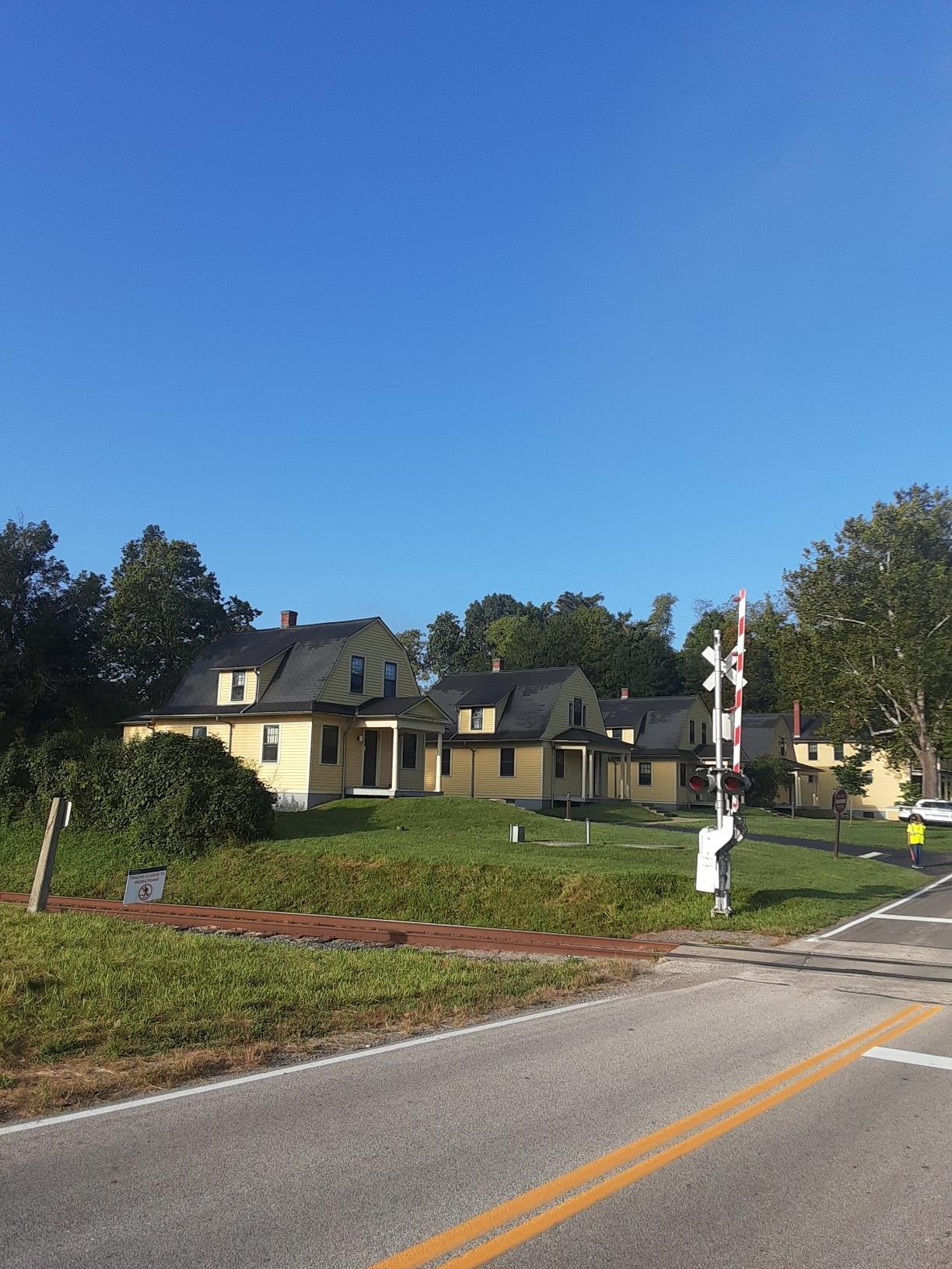 Yellow houses by a railroad crossing under a clear blue sky.