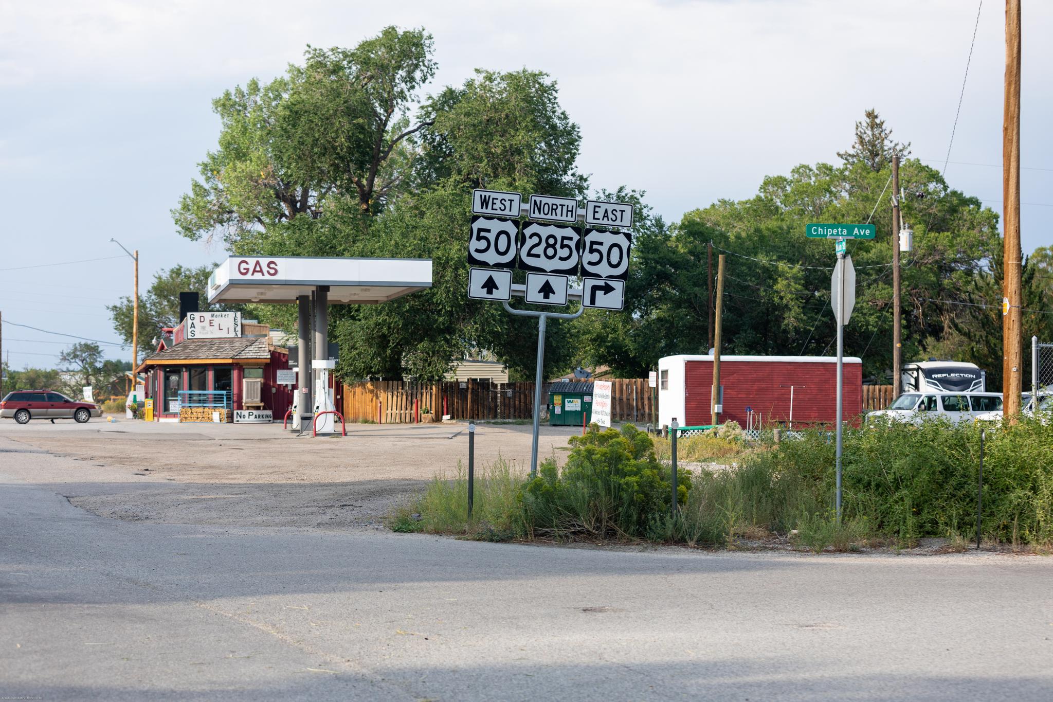 Gas station and road signs at an intersection on an overcast day.