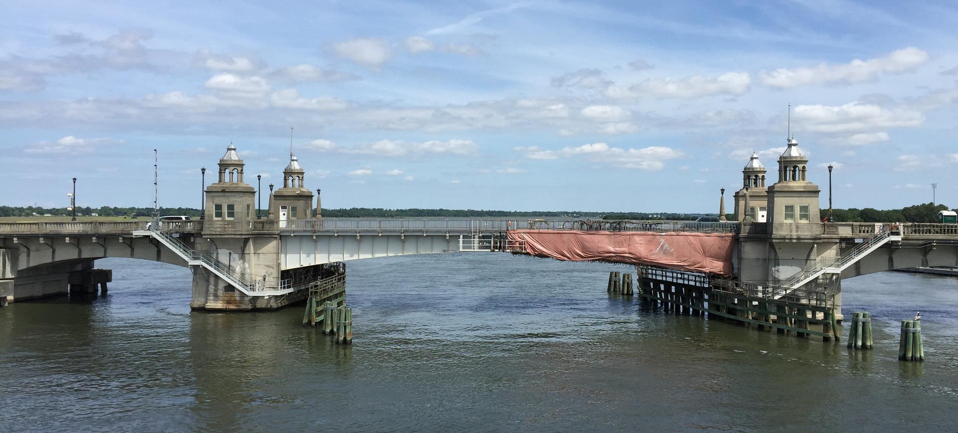 Large bridge with ornate towers spanning a river under a partly cloudy sky.