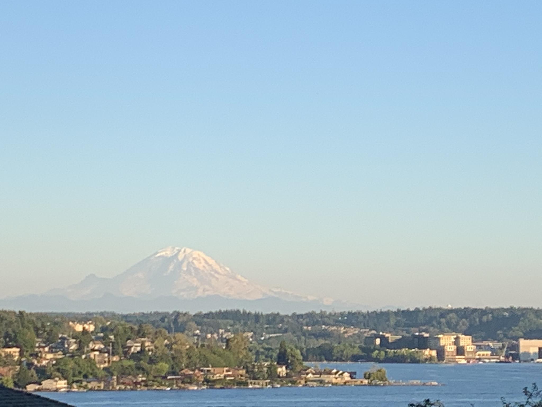 Distant snow-capped mountain over a body of water and a town.
