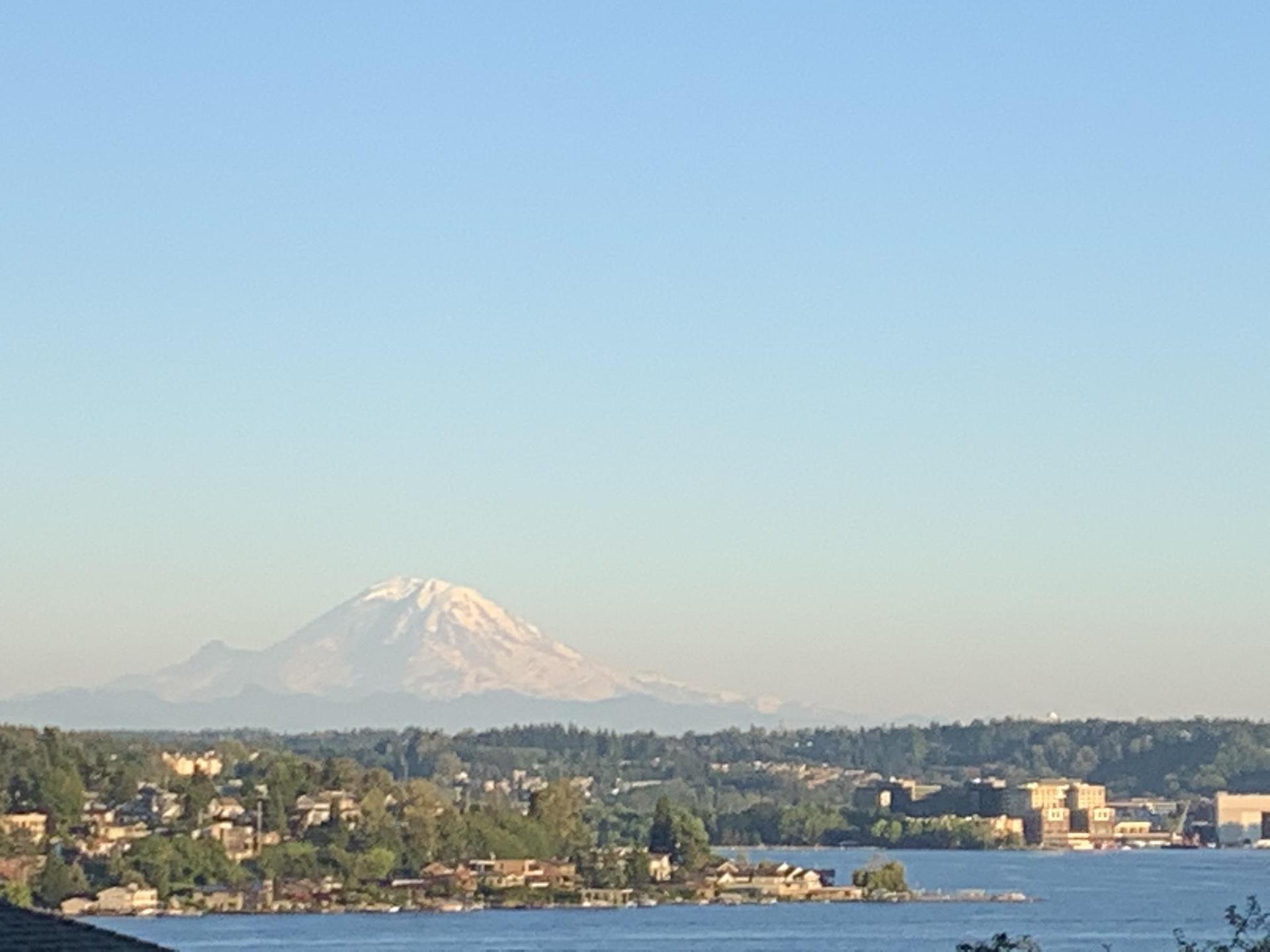 Distant snow-capped mountain over a body of water and a town.