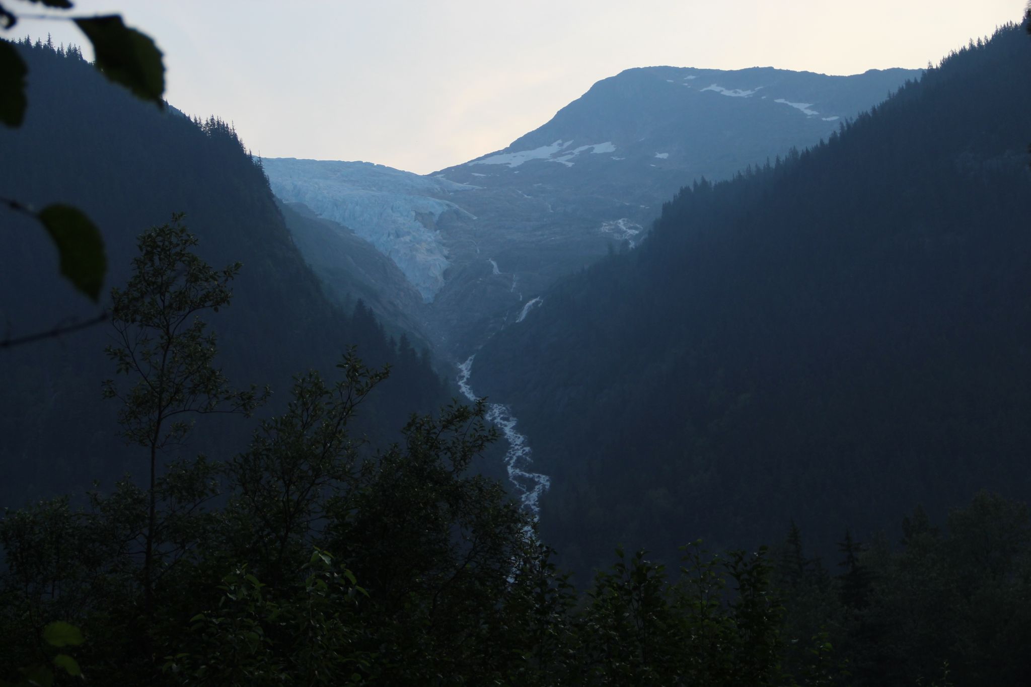 Dark mountain valley with a glacier and winding river under dim light. - Chilkoot Trail