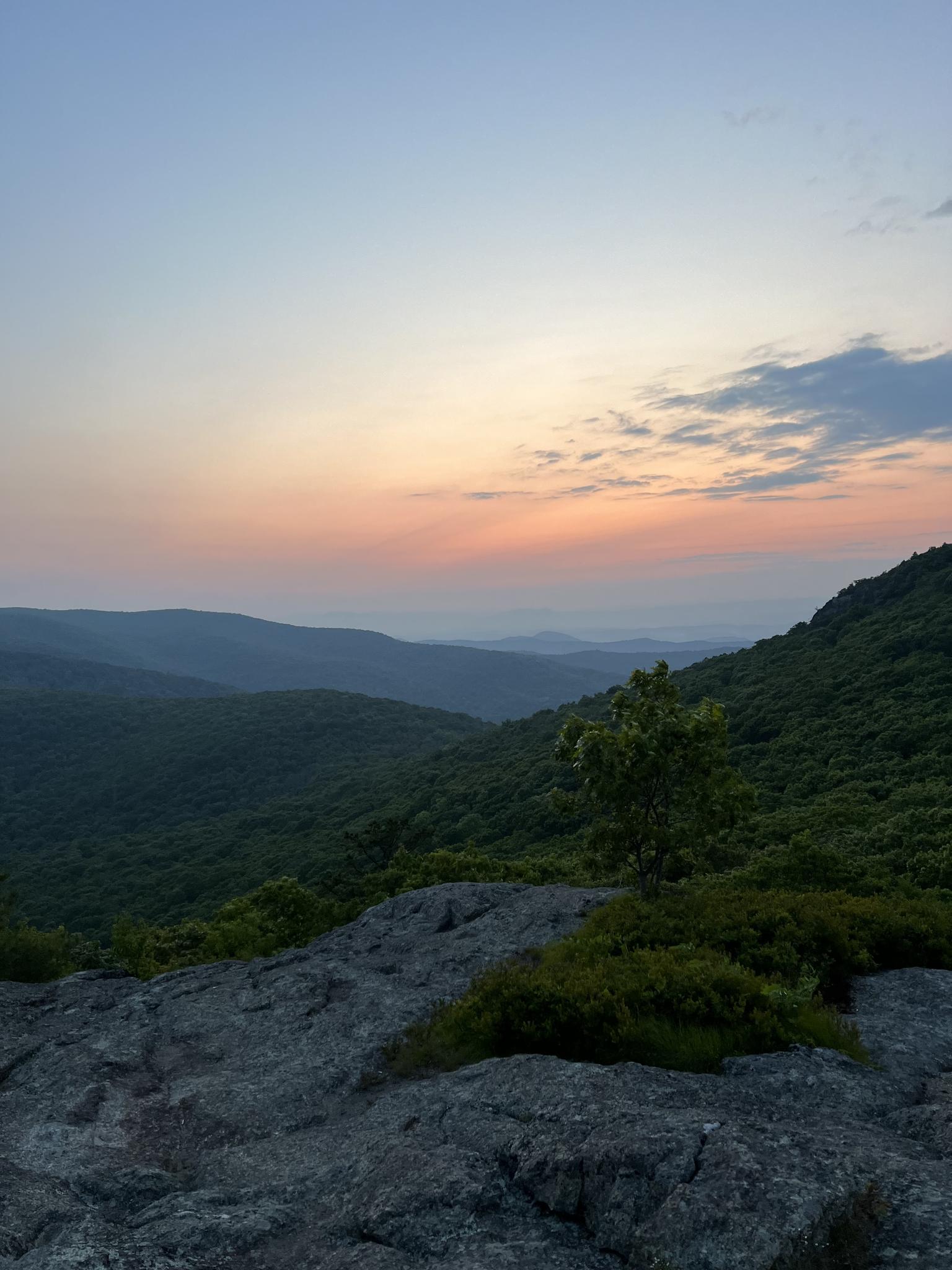 Serene mountain vista at twilight with a colorful sky and rocky foreground.