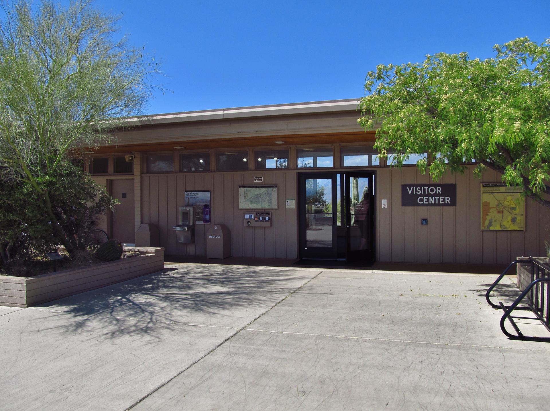 A visitor center building with desert plants under a clear blue sky.