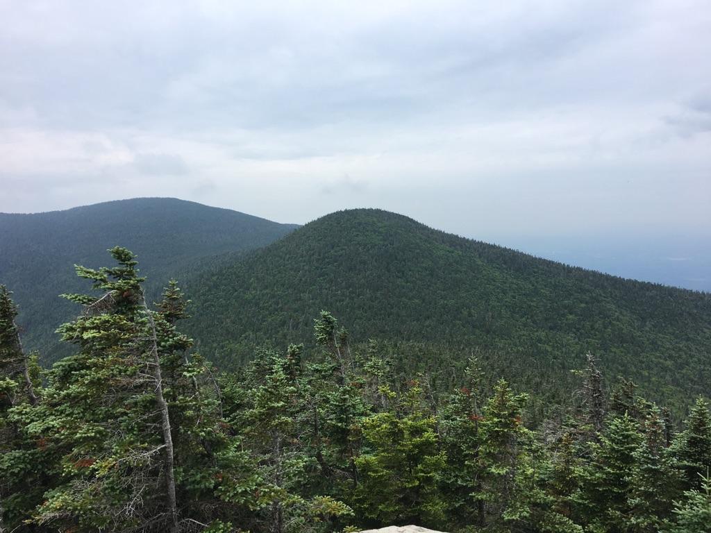 View of forested mountain peaks under an overcast sky.