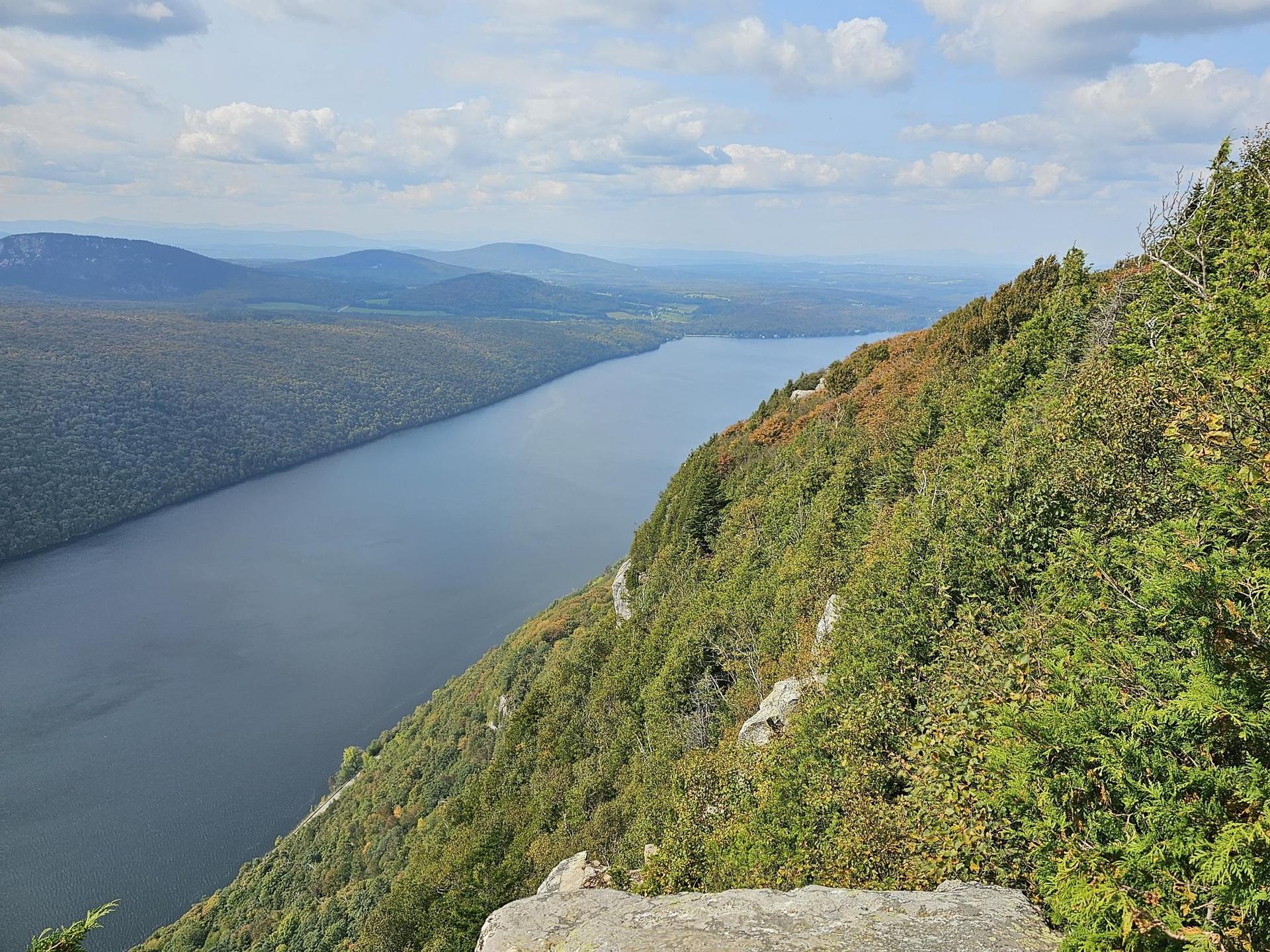 Panoramic view of a long body of water winding through forested hillsides.