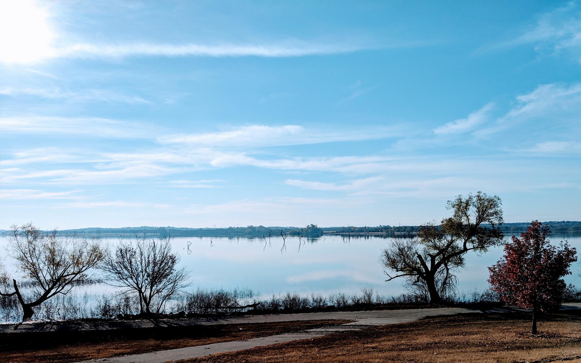 Bright sunny day over a calm lake with trees along the shoreline.