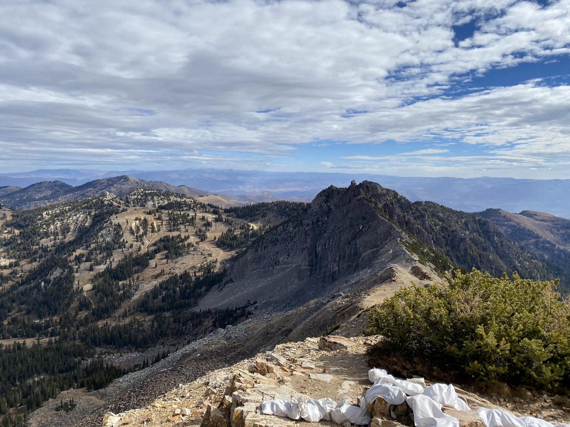 Panoramic view of a rugged mountain ridge with distant peaks under a cloudy sky.
