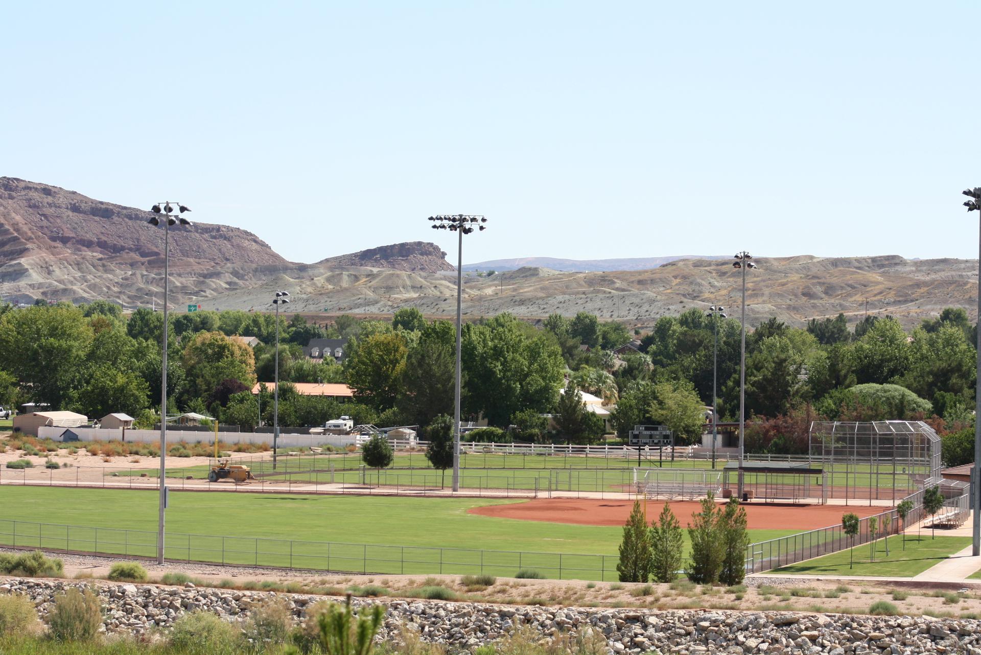 A bright daylight view of an empty baseball field with distant hills.